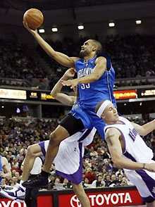 Orlando Magic's Grant Hill, top, shoots between Sacramento Kings' Mike Bibby, right, and Francisco Garcia, during the second quarter of their basketball game in Sacramento, Calif., Sunday, Jan. 15, 2006.