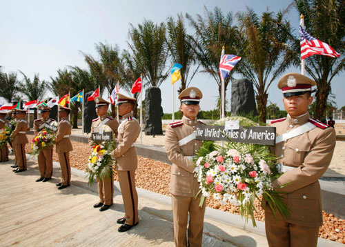 Police officers holds wreaths in front of flags from countries whose nationals died during the Indian Ocean tsunami at the opening ceremony of the Tsunami Victims Cemetery at Bang Muang Cemetery in Phang Nga province, about 900 km (597 miles) south of Bangkok, December 26, 2006.