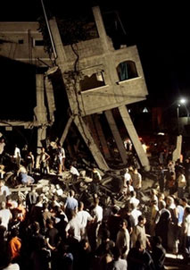 Palestinians gather in the rubble of a house destroyed in an explosion in Gaza City, early Wednesday, July 12, 2006. A huge explosion destroyed the home of a Hamas activist in Gaza City early Wednesday, killing five people, including two children, and wounding 15 others, as an Israeli warplane flew overhead, residents and hospital officials said. (AP Photo/Hatem Moussa)