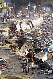 A man wheels his bicycle past the devastated area of Pangandaran, Indonesia July 18, 2006.